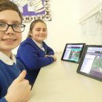 Two children smile to camera after completing a coding challenge in 2Code, the coding tool in Purple Mash