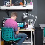 Student completing homework on desk in bedroom