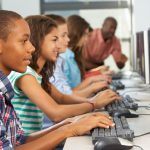 Row of students sitting at desktop computers.