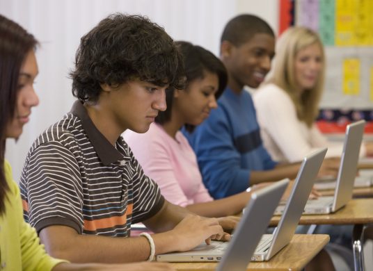 Students typing on laptops in classroom