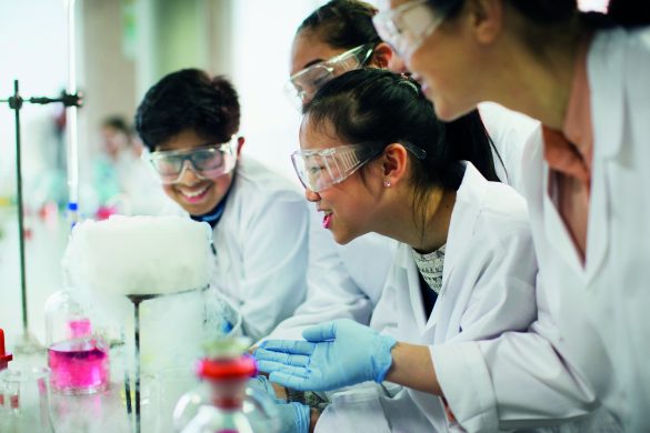 Curious students watching chemical reaction, conducting scientific experiment in laboratory classroom.